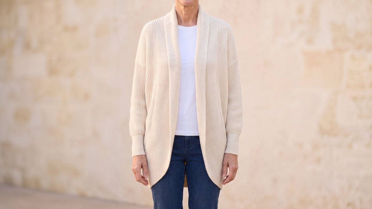 Woman wearing a cream shawl collar cardigan from Elina Blanc